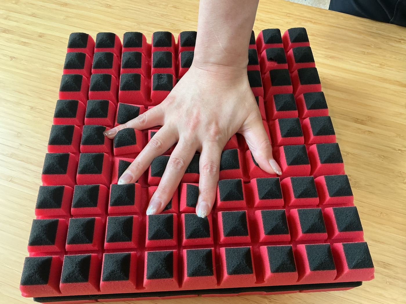 点で支えるマットレスの凹凸構造を手で押して確かめる様子